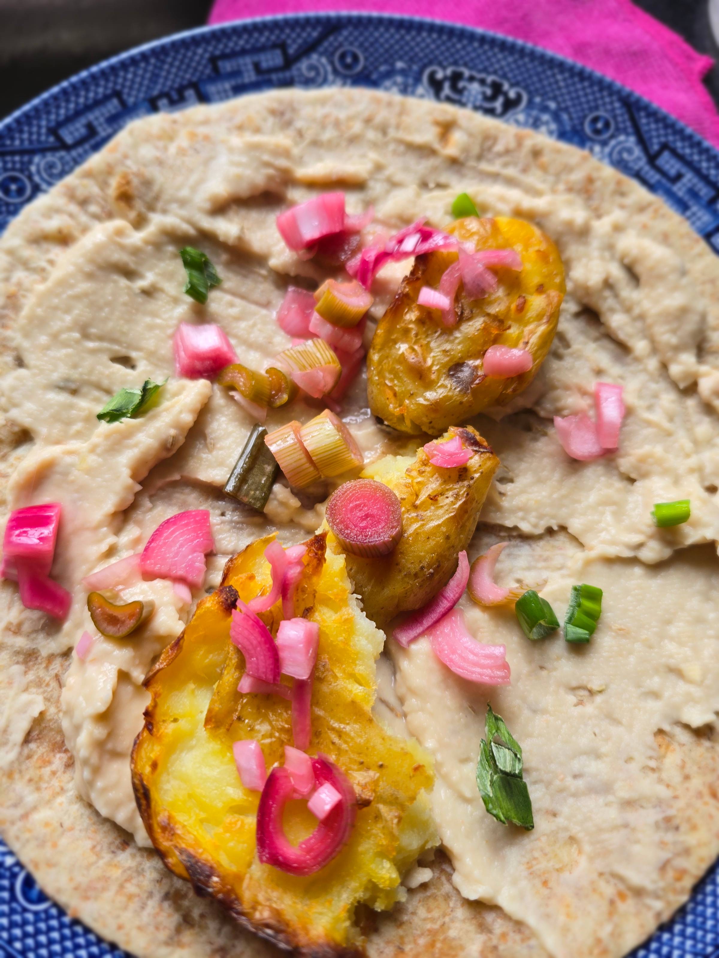 Tortilla wrap with bean hummus, crispy roast potatoes and pickled purple salad onions
