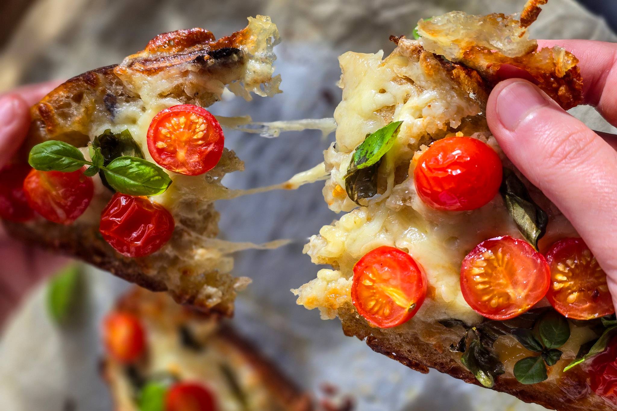 Cheesy sourdough bread pizza being torn
