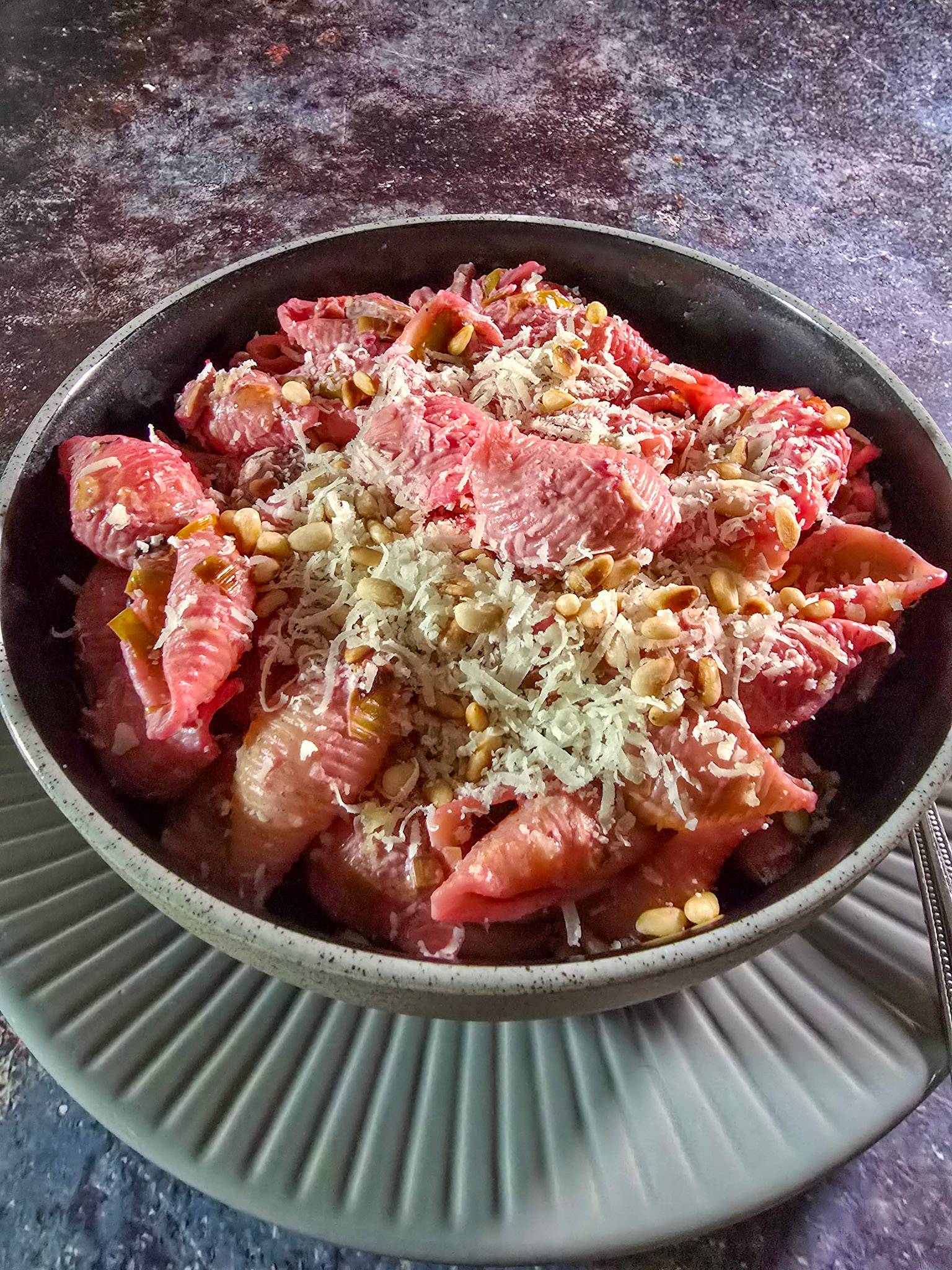 A bowl of beetroot pasta with parmesan and pinenuts