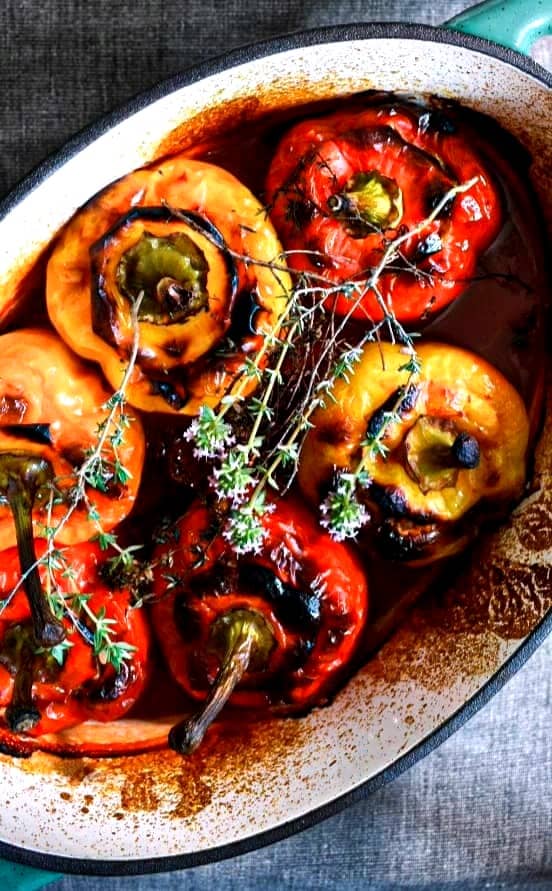 Stuffed red and yellow bell peppers with thyme flowers on top.