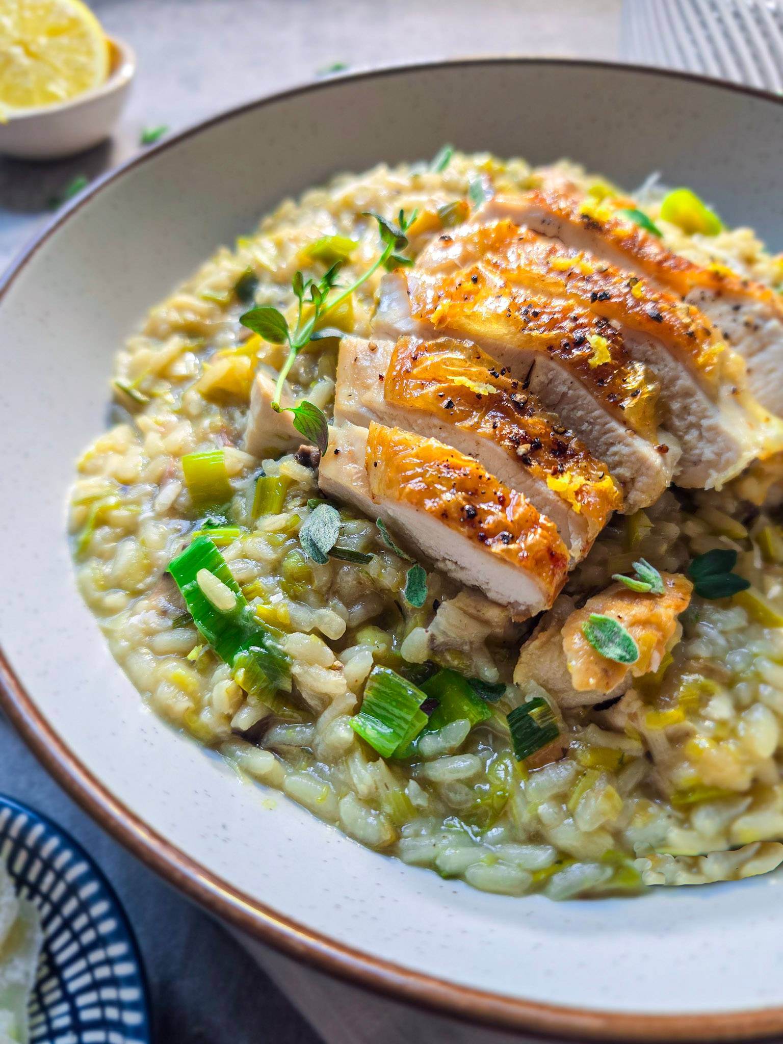 A chicken and leek risotto with golden lemon pepper chicken on top.