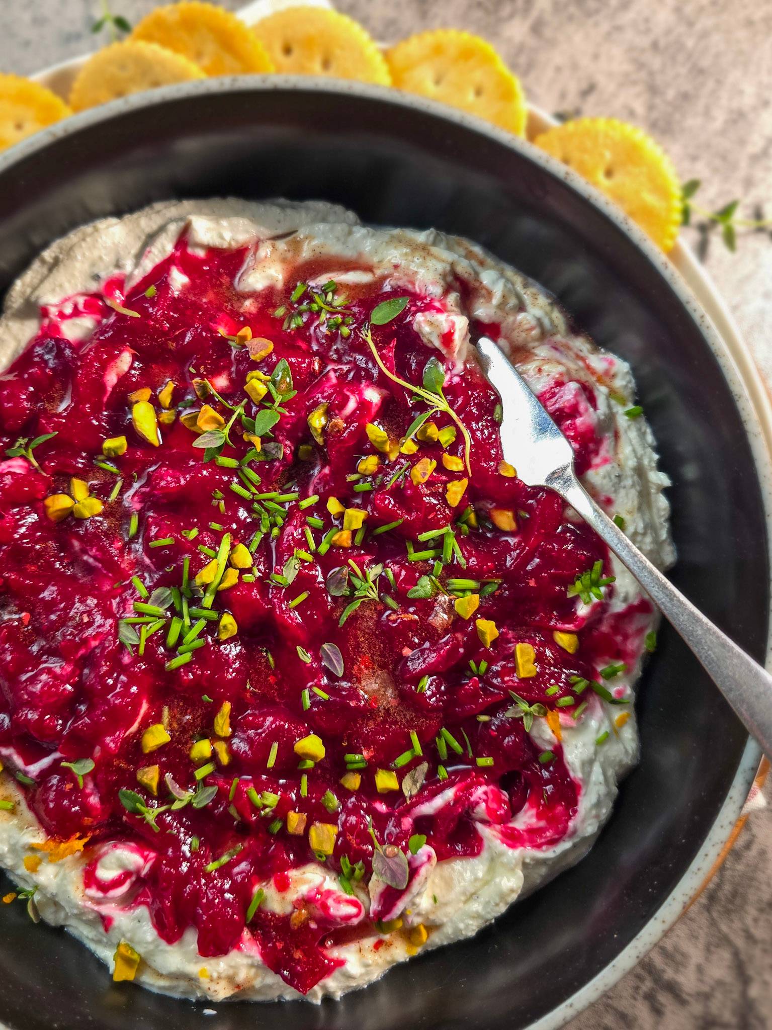 cranberry whipped feta dip topped with herbs and pistachios.
