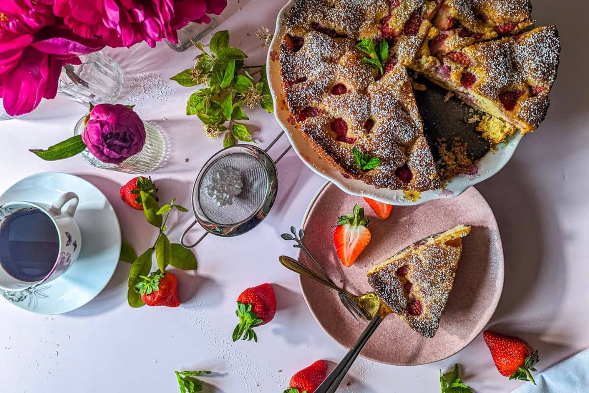 Strawberry cake served alongside a cup of coffee