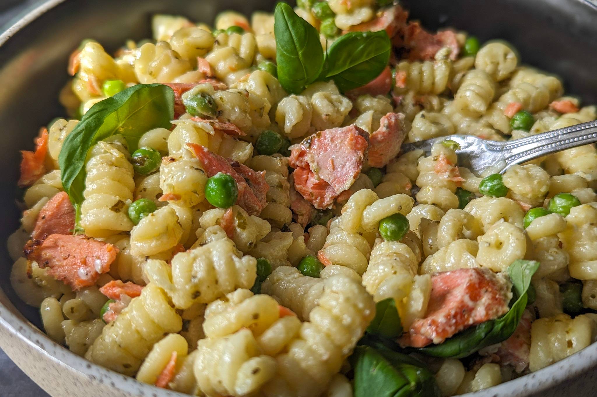 A close up of salmon pasta with peas and basil.