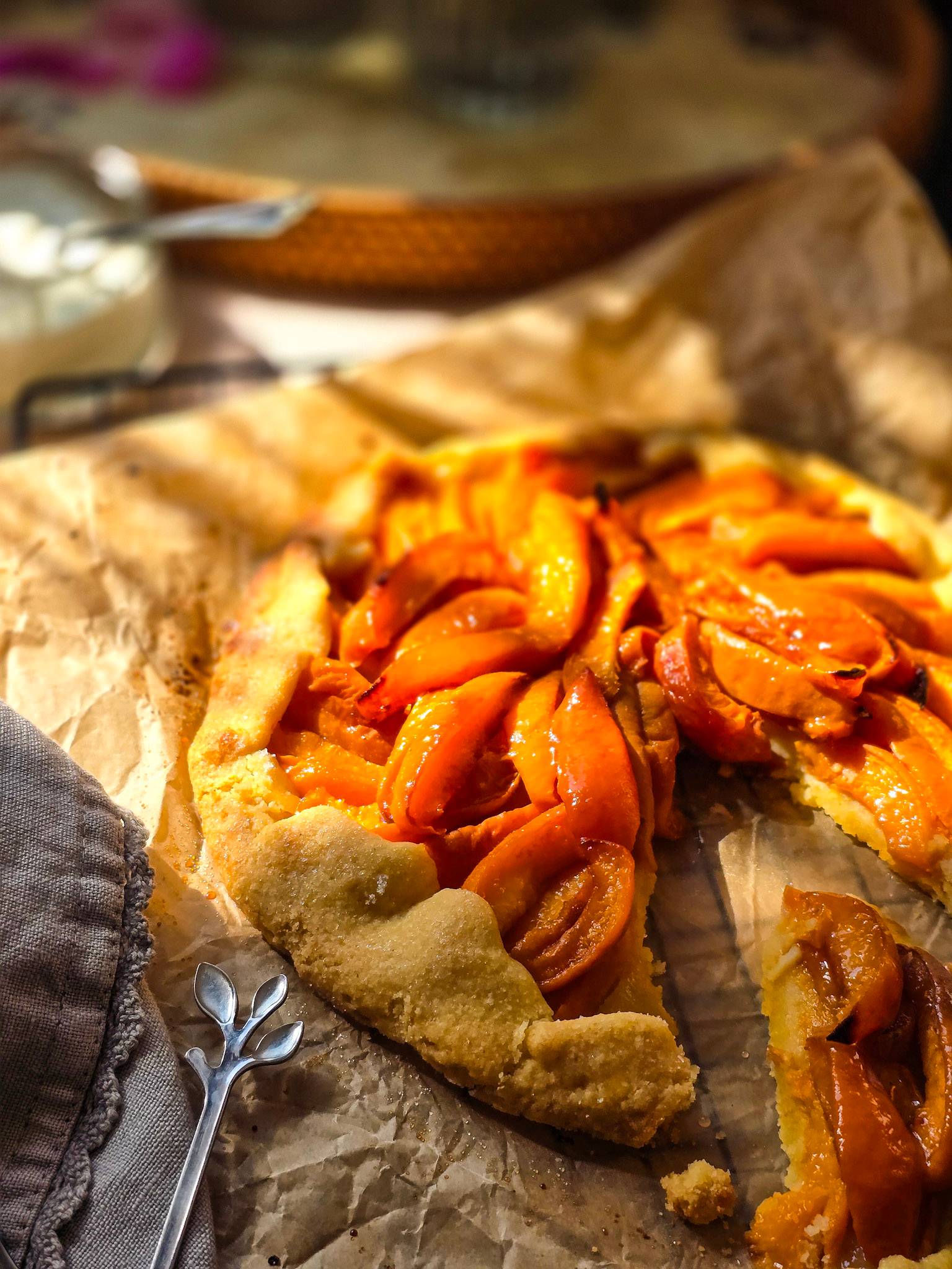 Apricot galette, with a slice cut, on parchment paper.