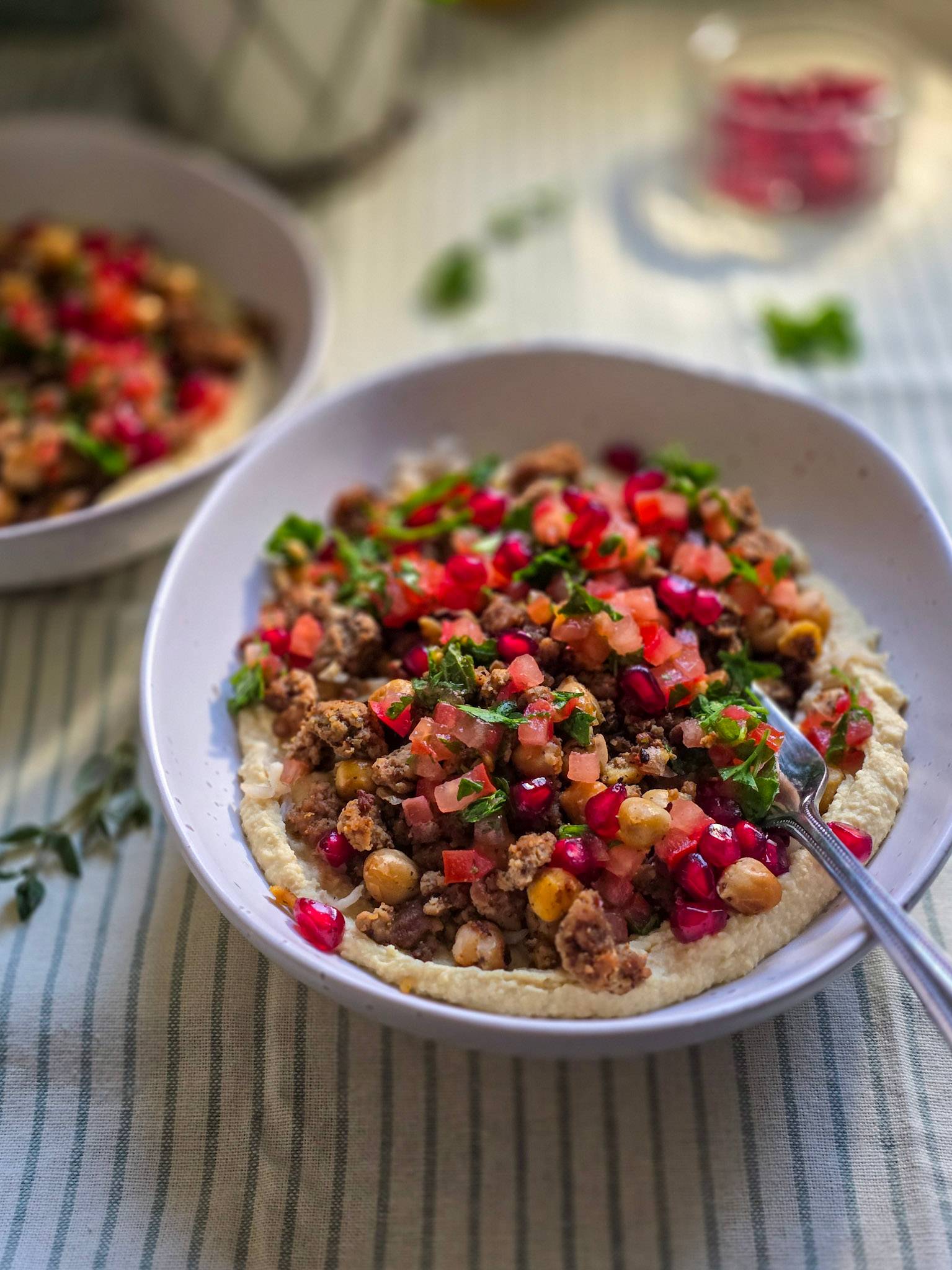 A ground lamb bowl topped with fresh tomatoes salsa, crispy chickpeas on a layer of hummus.