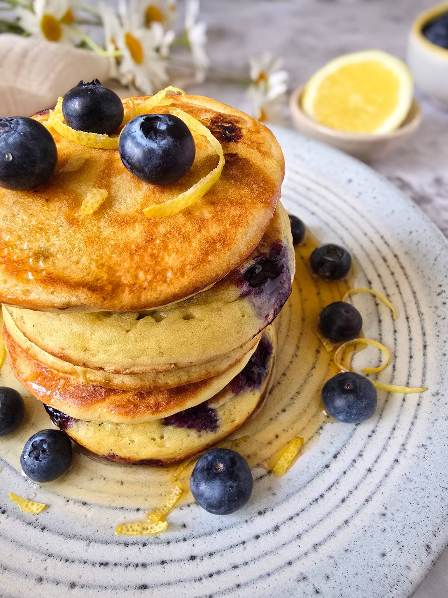 Stack of sourdough lemon pancakes with blueberries and lemon zest curls.