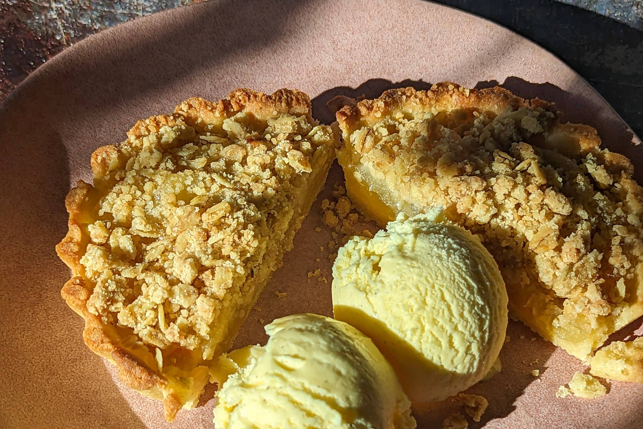 Individual apple crumble tarts with spiced apple filling and oat topping served with vanilla ice cream