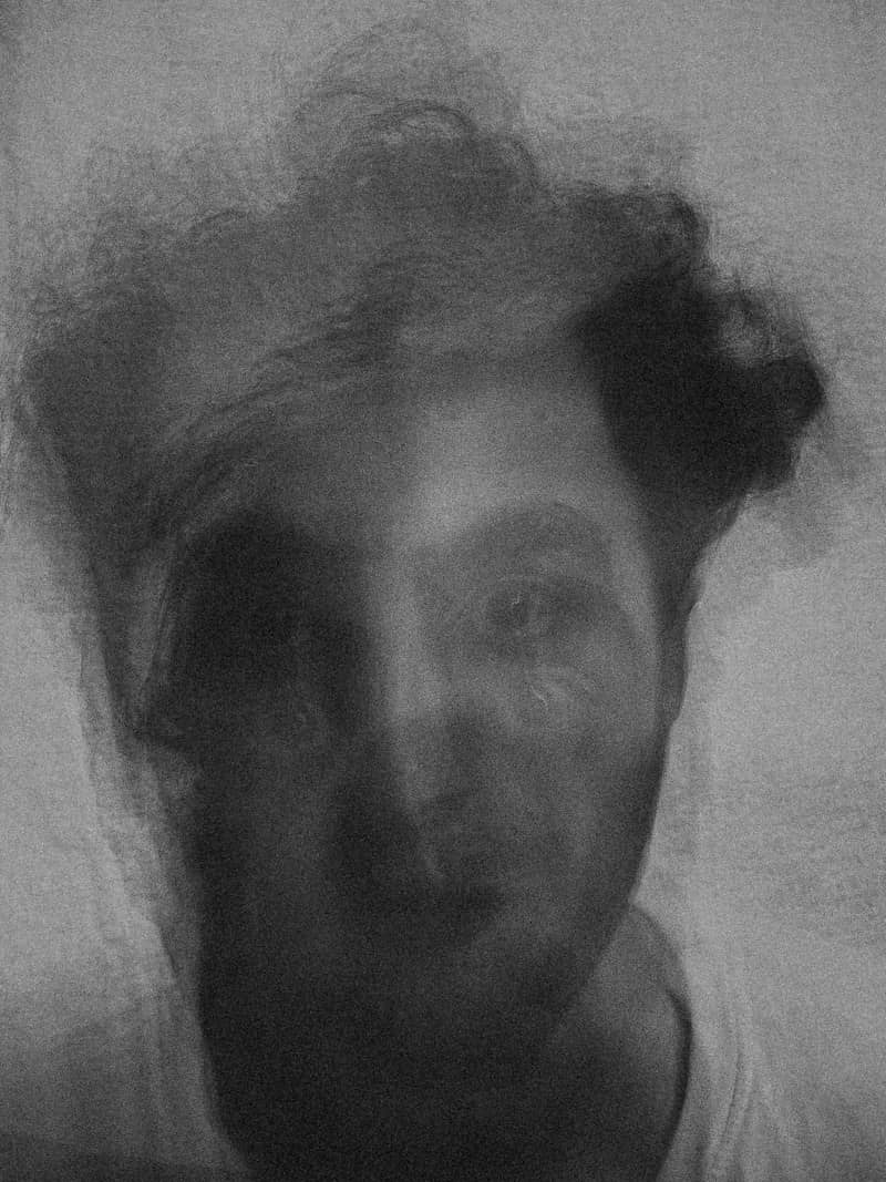 A blurry monochromatic portrait of a person with dark hair