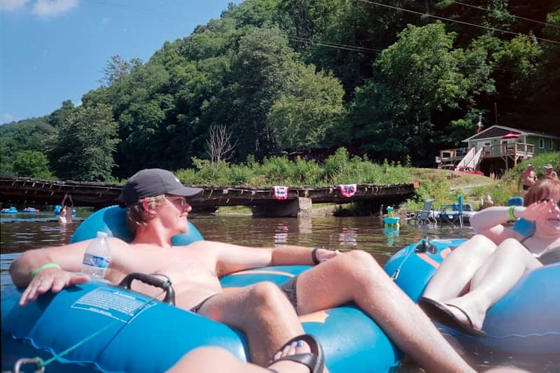 Man tubing on a river with forested hills