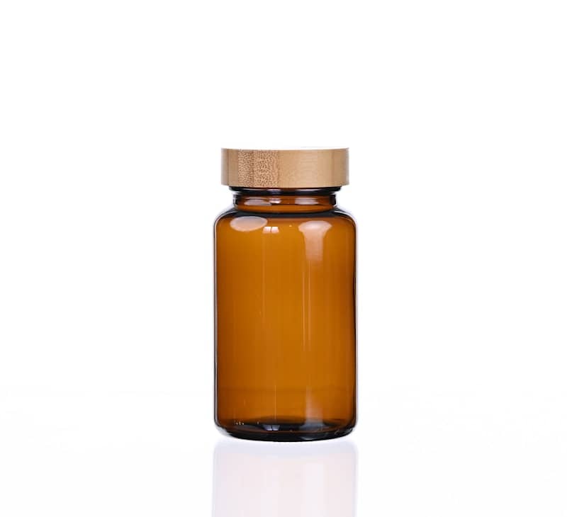 Amber glass bottle with wooden lid on white background