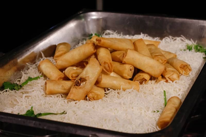 Golden spring rolls piled on a bed of white noodles