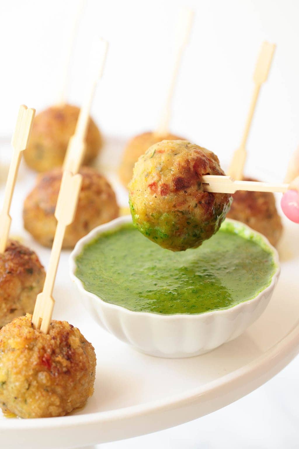 Vietnamese chicken meatballs being dipped in a bright green lemongrass cilantro sauce 
