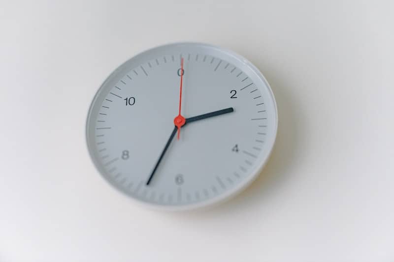 Minimalist white wall clock on a plain white background.