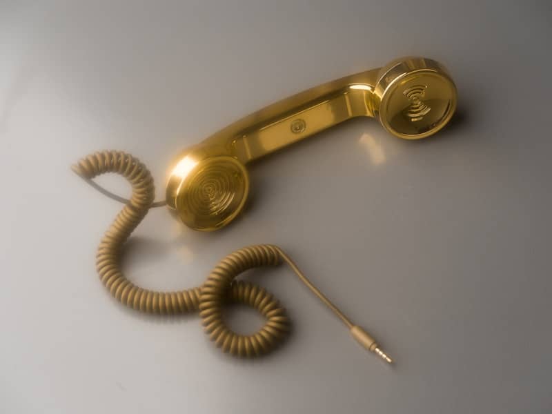 A shiny gold telephone receiver with coiled cord