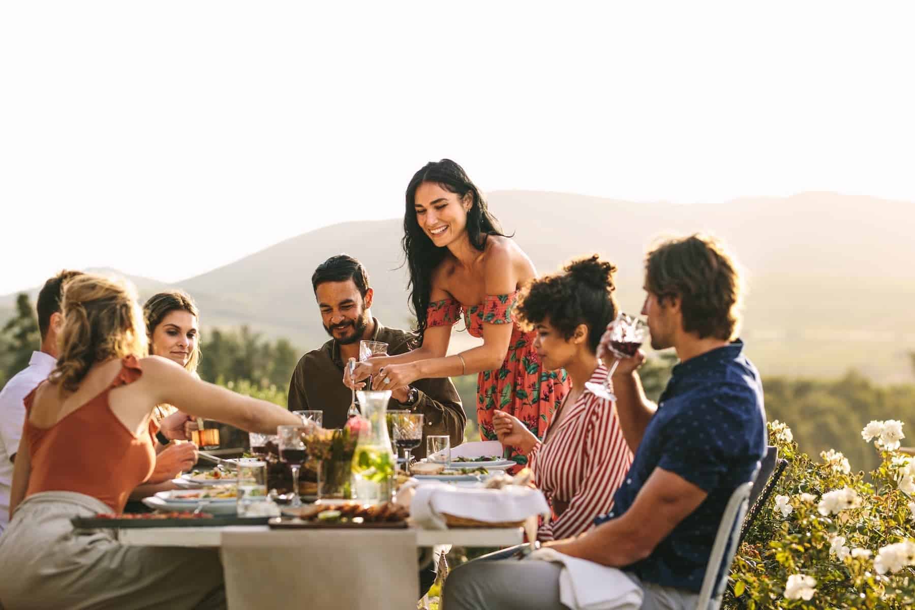 Loved ones gather at an outdoor dinner table during sunset, savoring delicious foods from the Mediterranean diet.