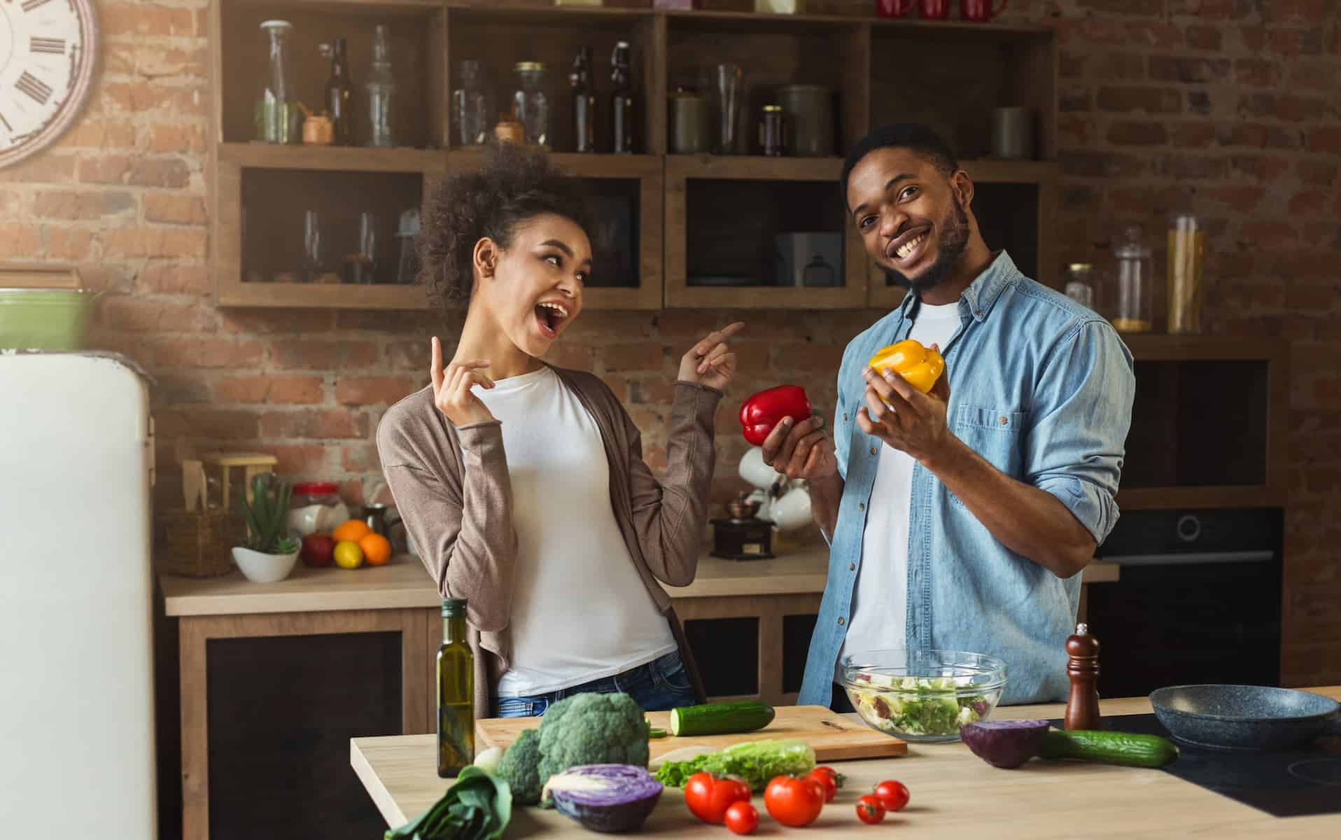 A happy couple prepares a colorful salad, a great example of how to start eating healthy with fresh veggies.
