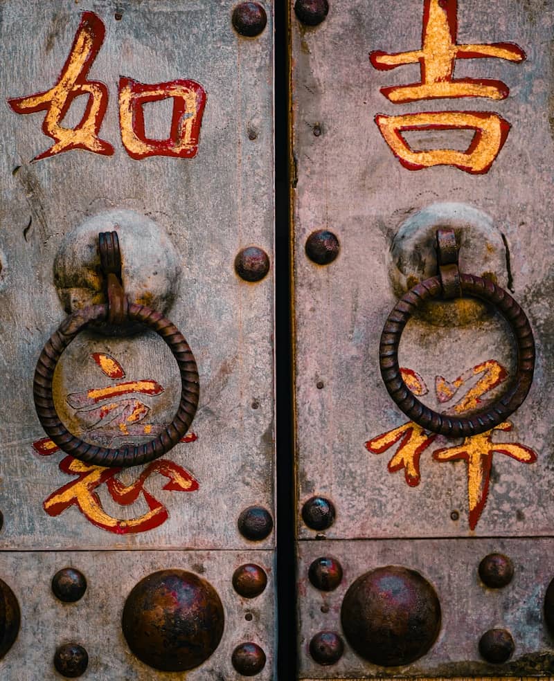 Ornate metal doors with chinese characters and ring handles