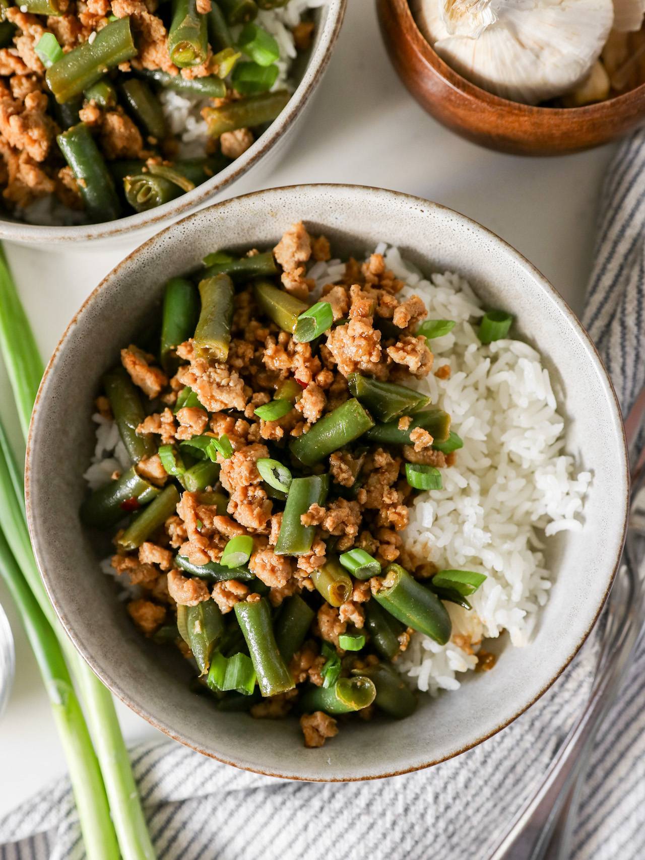 ground turkey green bean stir fry in a serving bowl with a fork and knife on the side.