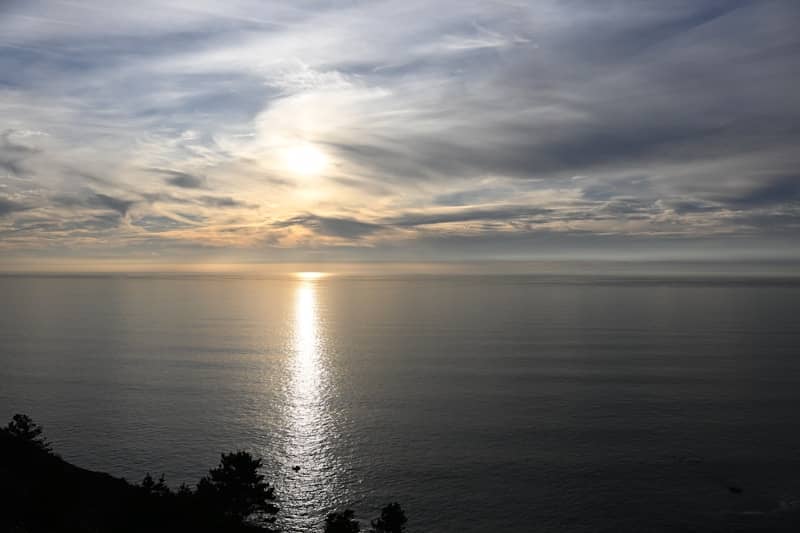 Sunset over a calm ocean with dramatic clouds.