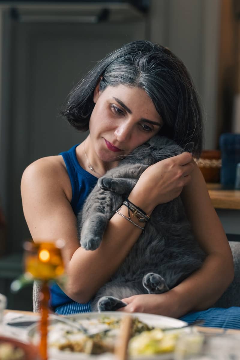 Woman lovingly hugs a large gray cat.