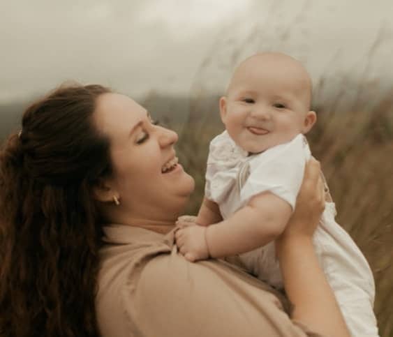 Mother holding her smiling baby outdoors