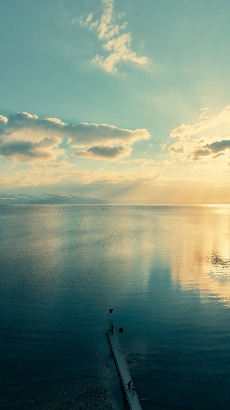 Calm sea with a pier at sunset