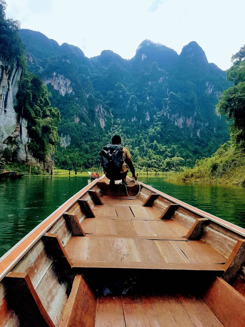 Man in boat approaching lush green mountains