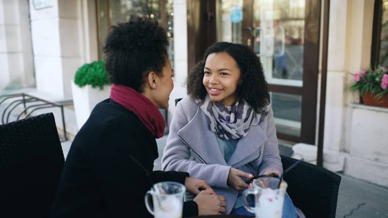 Two women talking at an outdoor cafe.