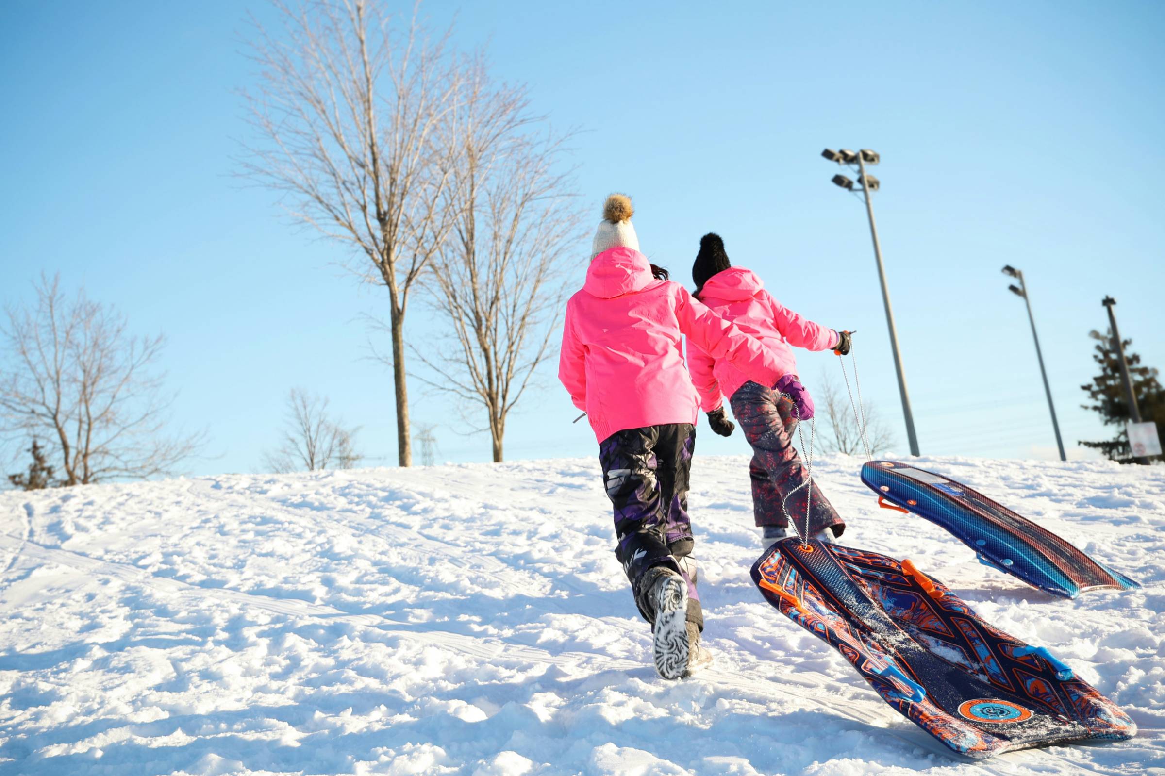 two people with sleds walking up a snowy hill