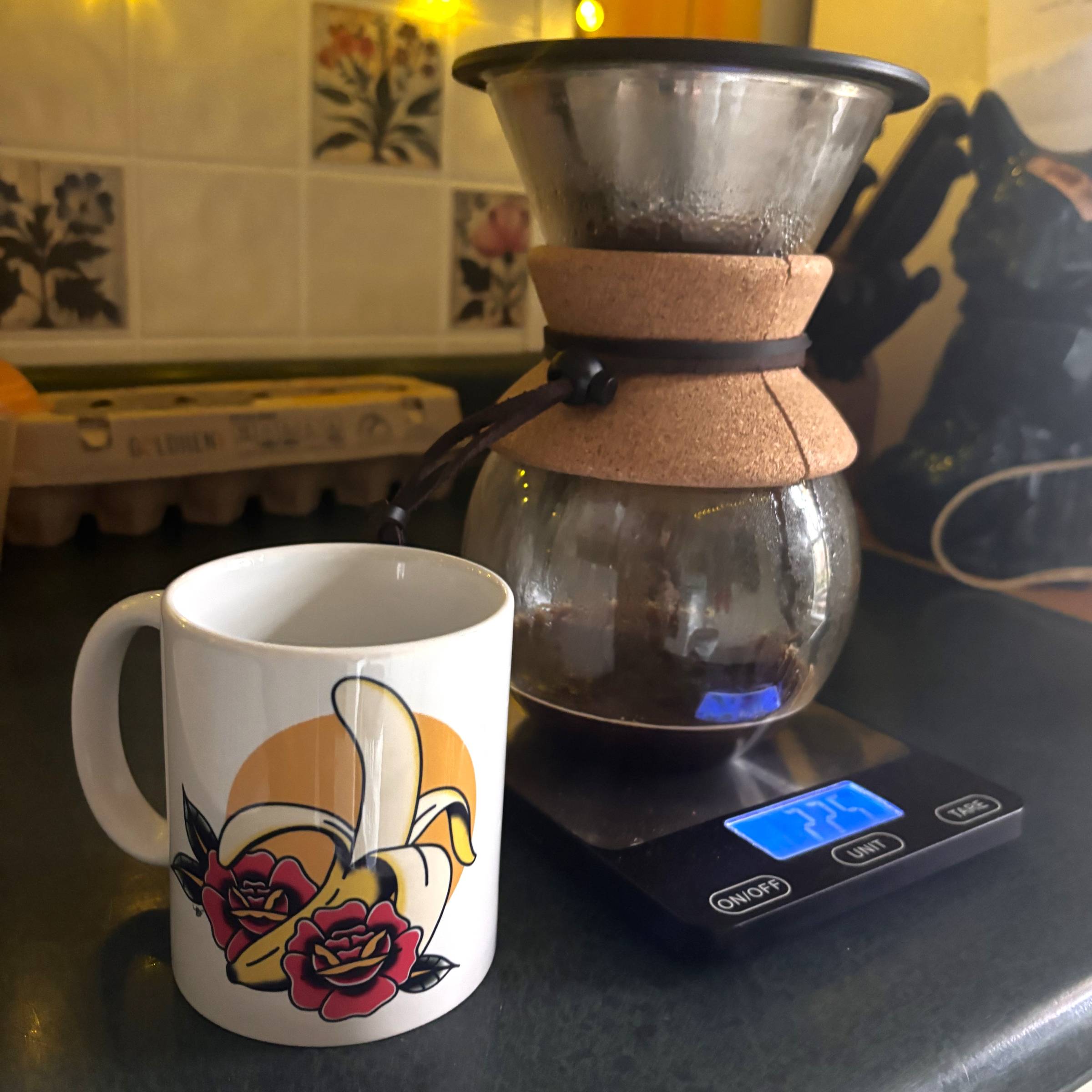 a pour-over coffee maker on a digital scale beside a coffee mug