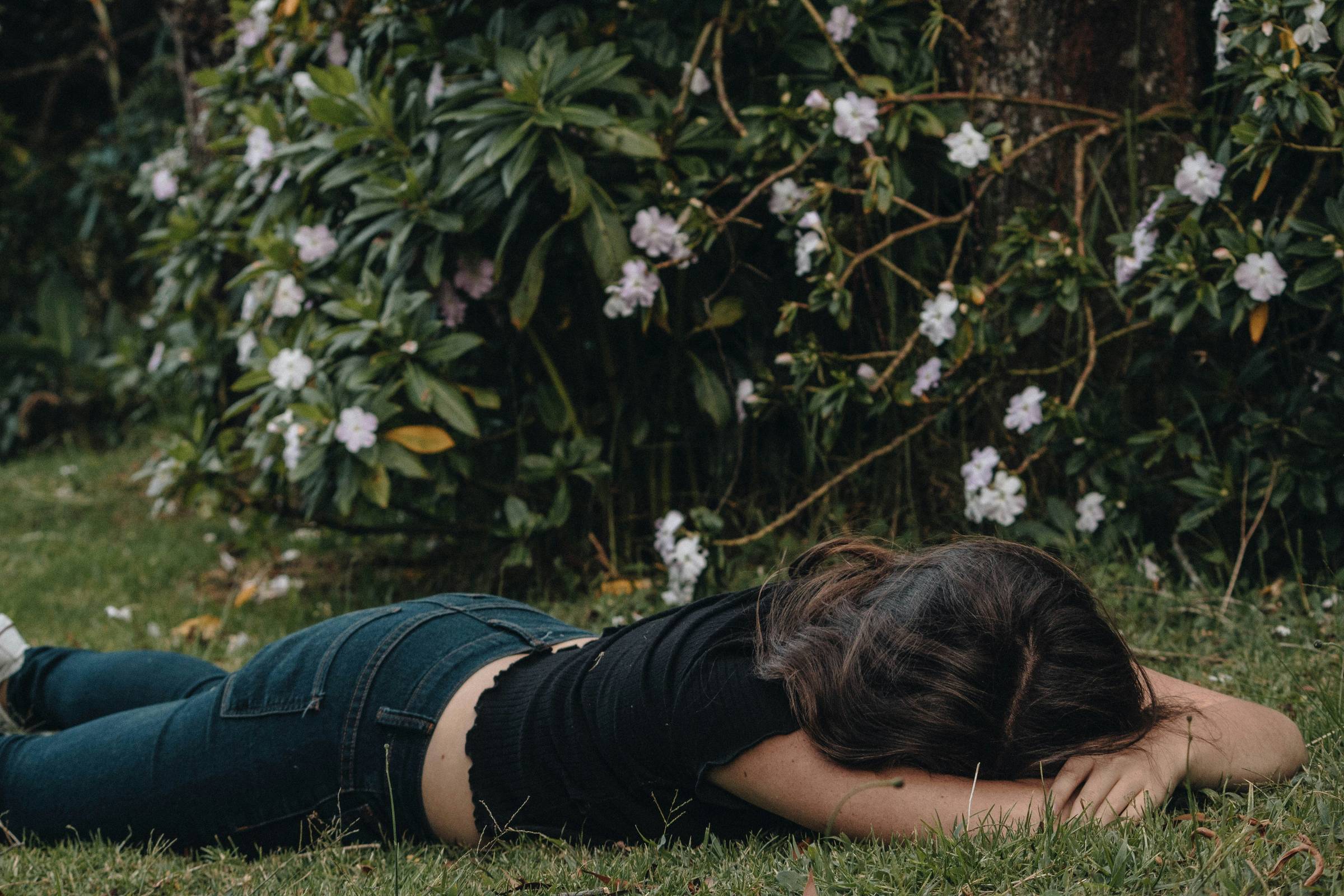 woman laying face down in the grass with her head in her arms
