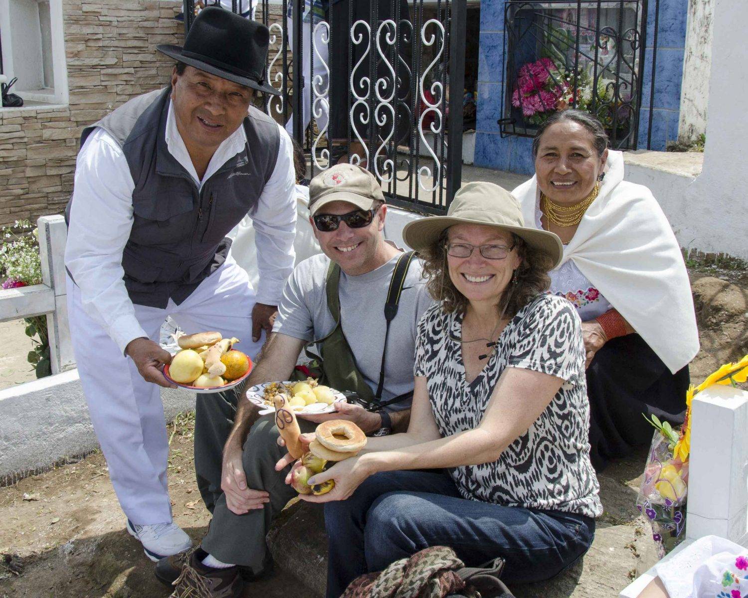 Image: Two American visitors sit between two Ecuadorian hosts, while holding plates of food and smiling for the camera