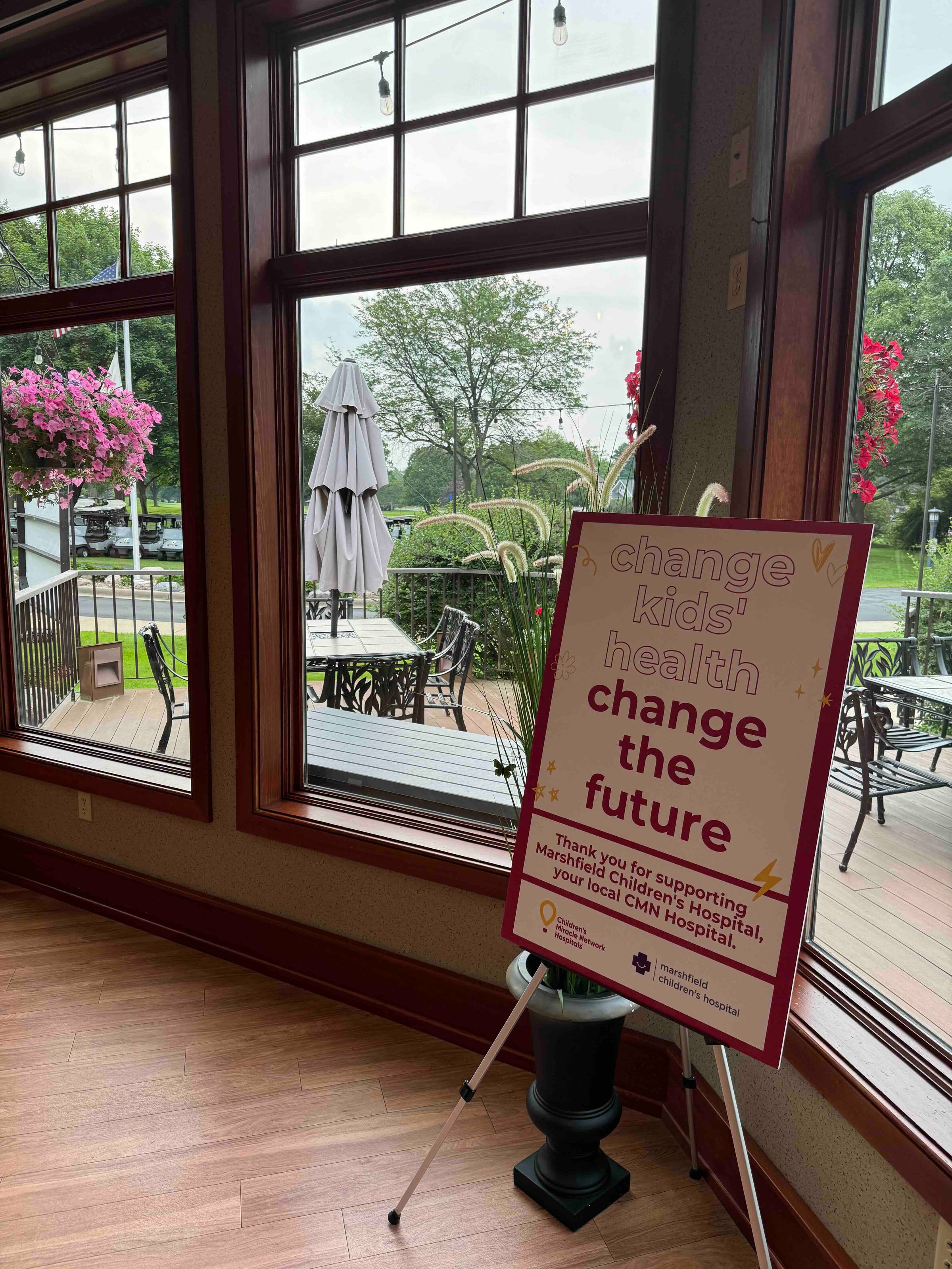 A sign that says "change kids' health, change the future" at a charity golf tournamentt