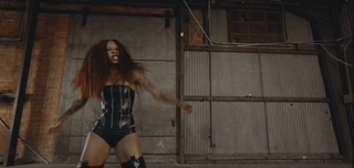 A gif of Rico Nasty flexing her arms in her music video "Son of a Gun."