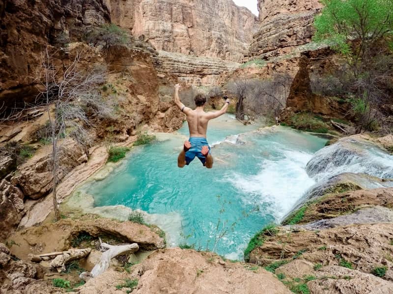 time lapse photography of man jumping on waterfalls