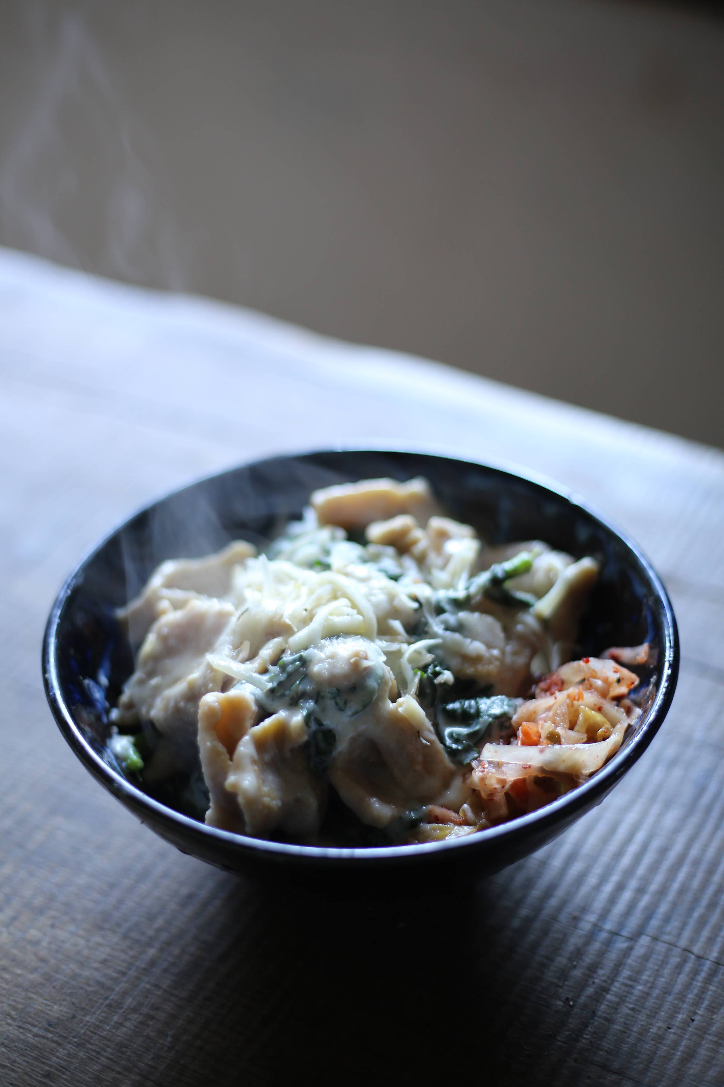 bowl of sourdough pasta and kale with cheesy sauce with kimchi on the side