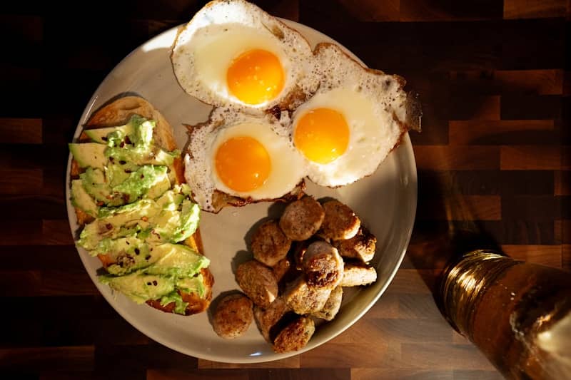 A plate of food with eggs, potatoes, and avocado