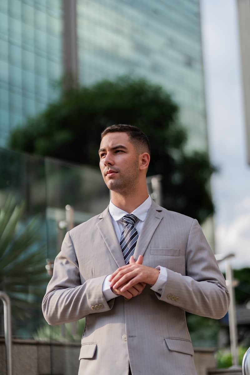 A businessman in a suit stands outside a building.