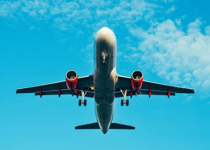Airplane flying overhead in a bright blue sky.