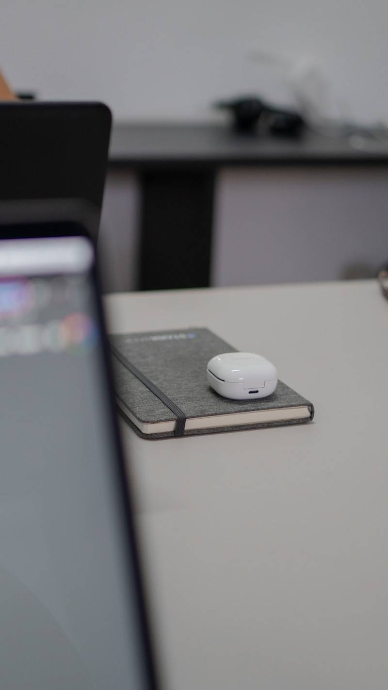 A notebook with wireless earbuds on a desk.