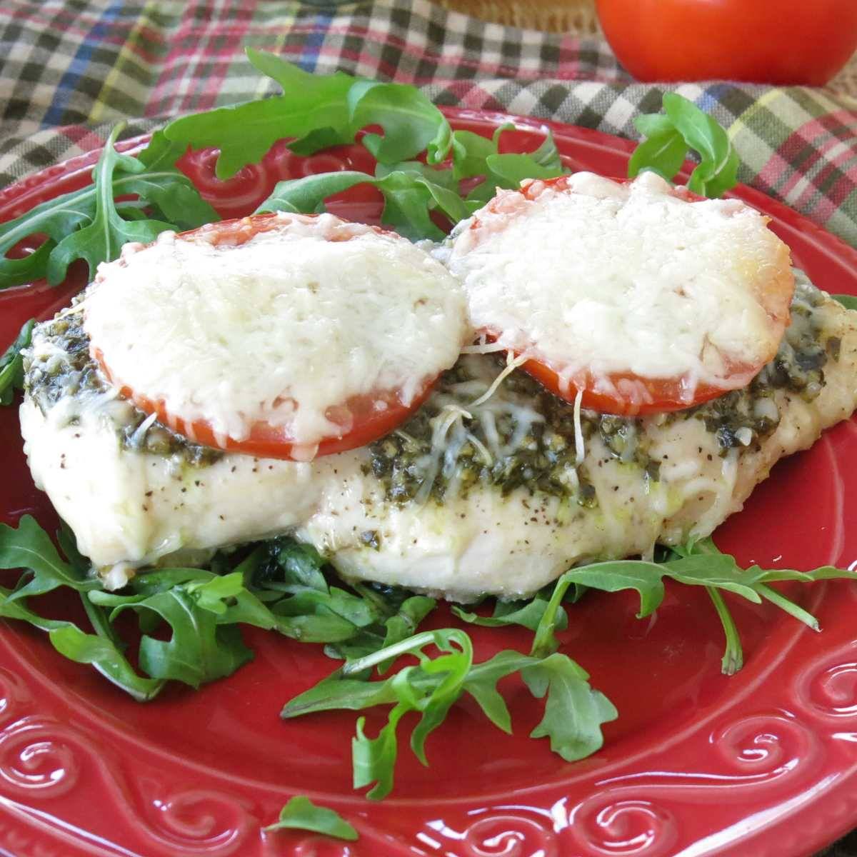 Baked pesto chicken on a red plate.