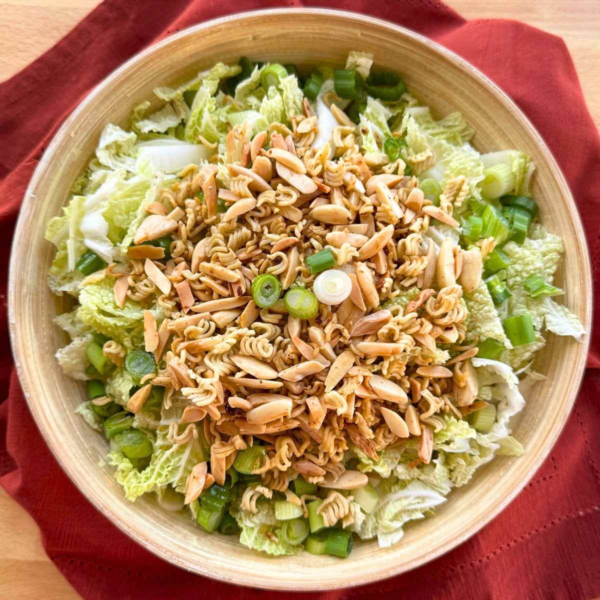 Napa cabbage salad with a crunchy ramen topping in a bowl.