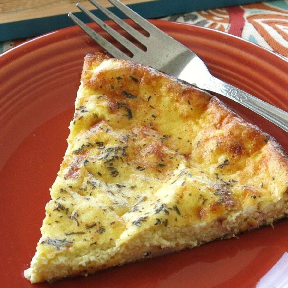 Slice of crustless quiche on a plate with a fork.