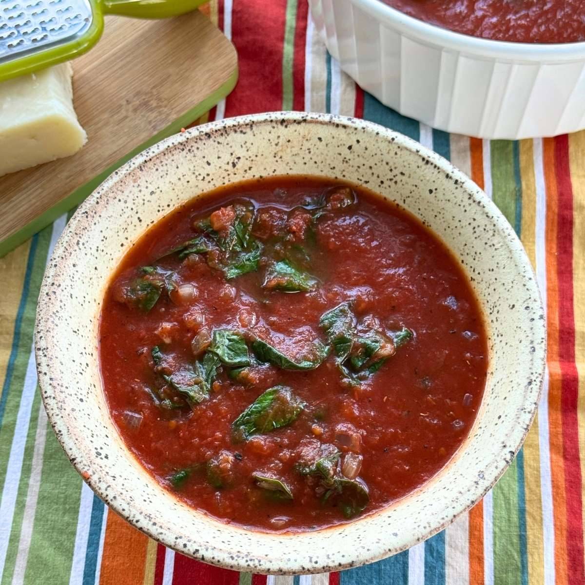 Tomato Florentine soup in a cream bowl on a striped napkin.