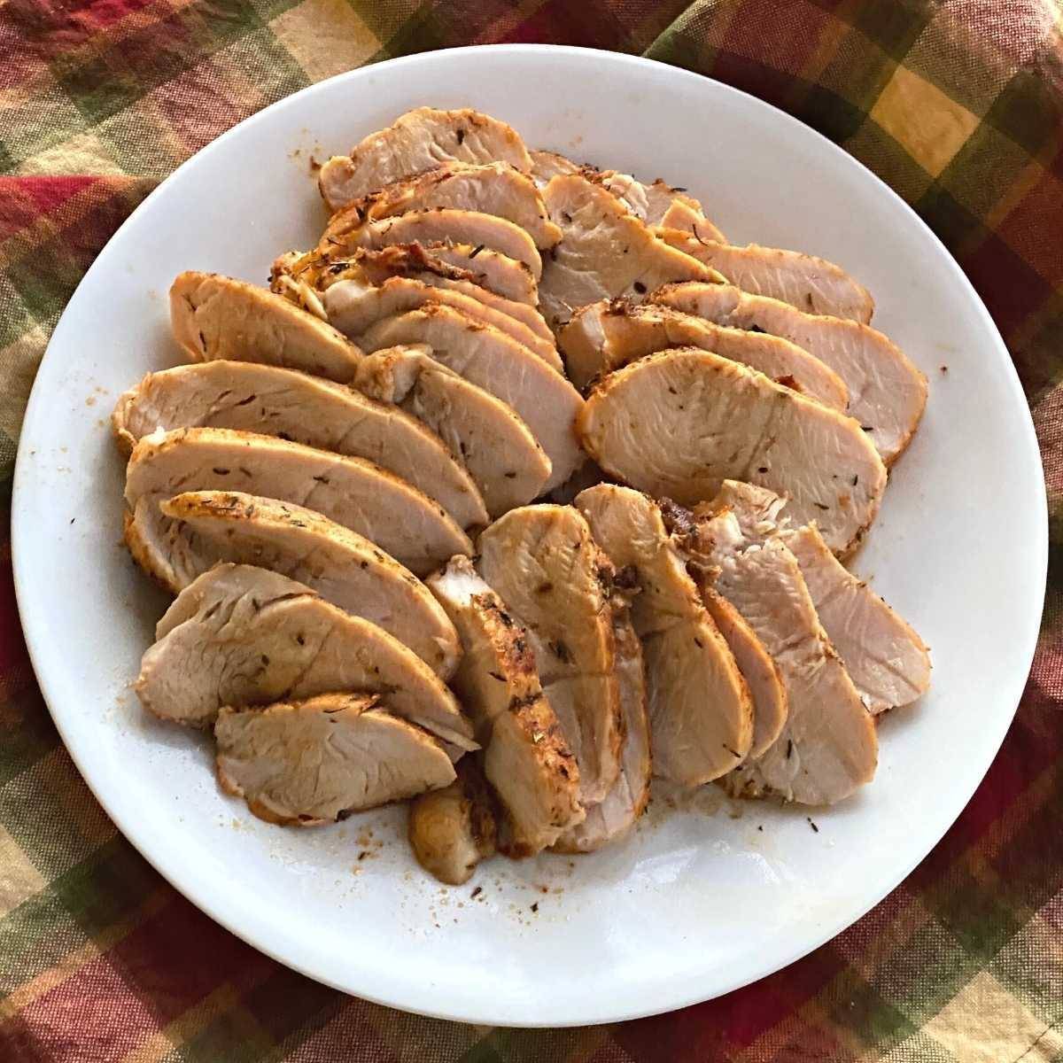 Sliced of turkey tenderloin on a a white plate.