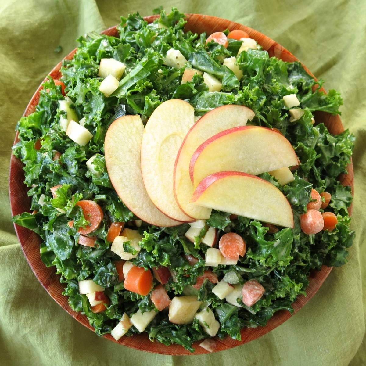 Kale apple slaw in a brown bowl with apple slices fanned on top.