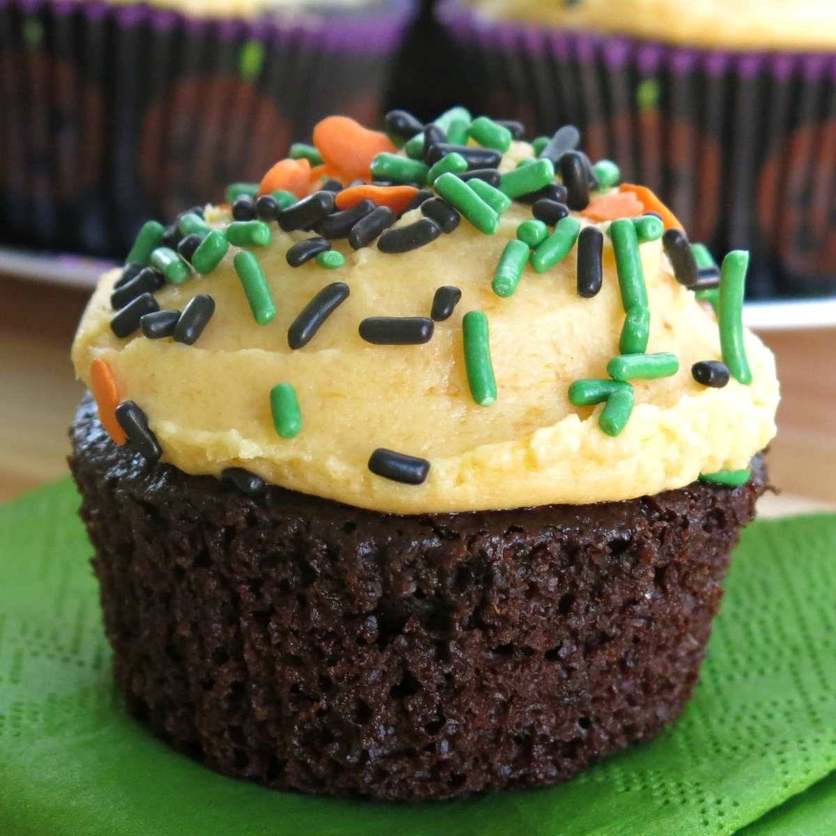 Chocolate pumpkin cupcake on a green paper napkin.