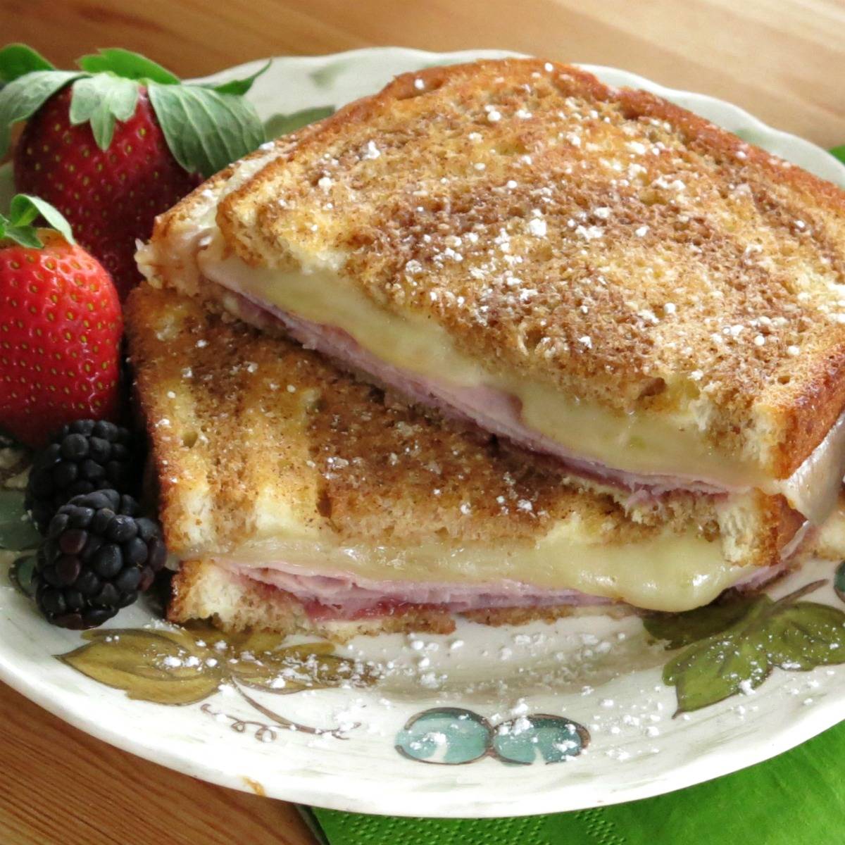Monte cristo grilled cheese cut in half and stacked on a plate.