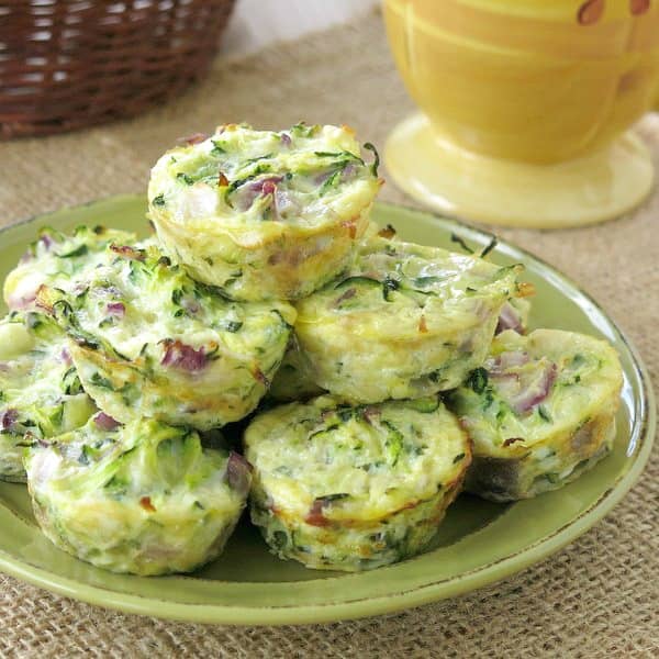 Zucchini egg bites stacked on a green plate.